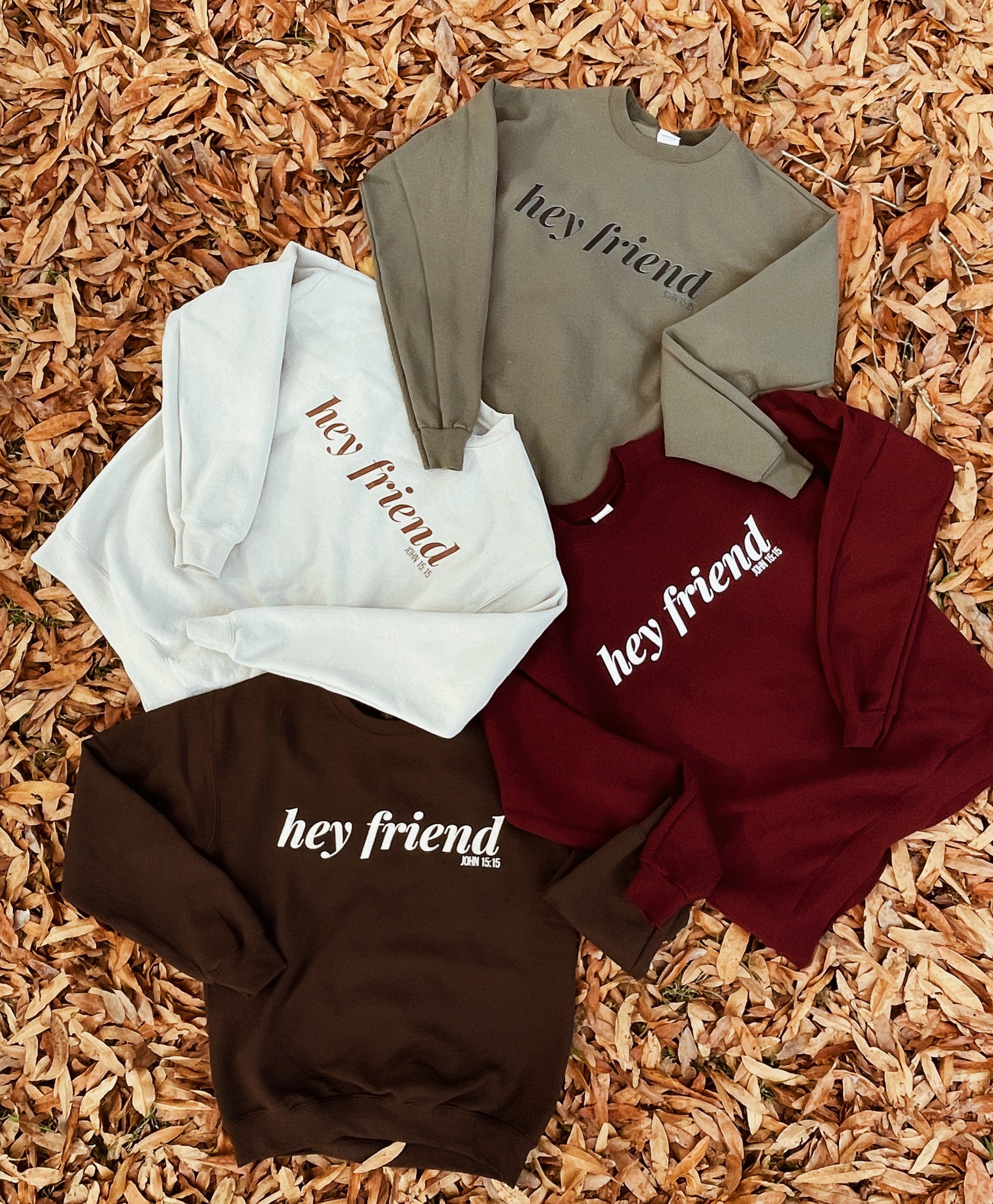 Four sweatshirts with 'hey friend' text on a wooden surface